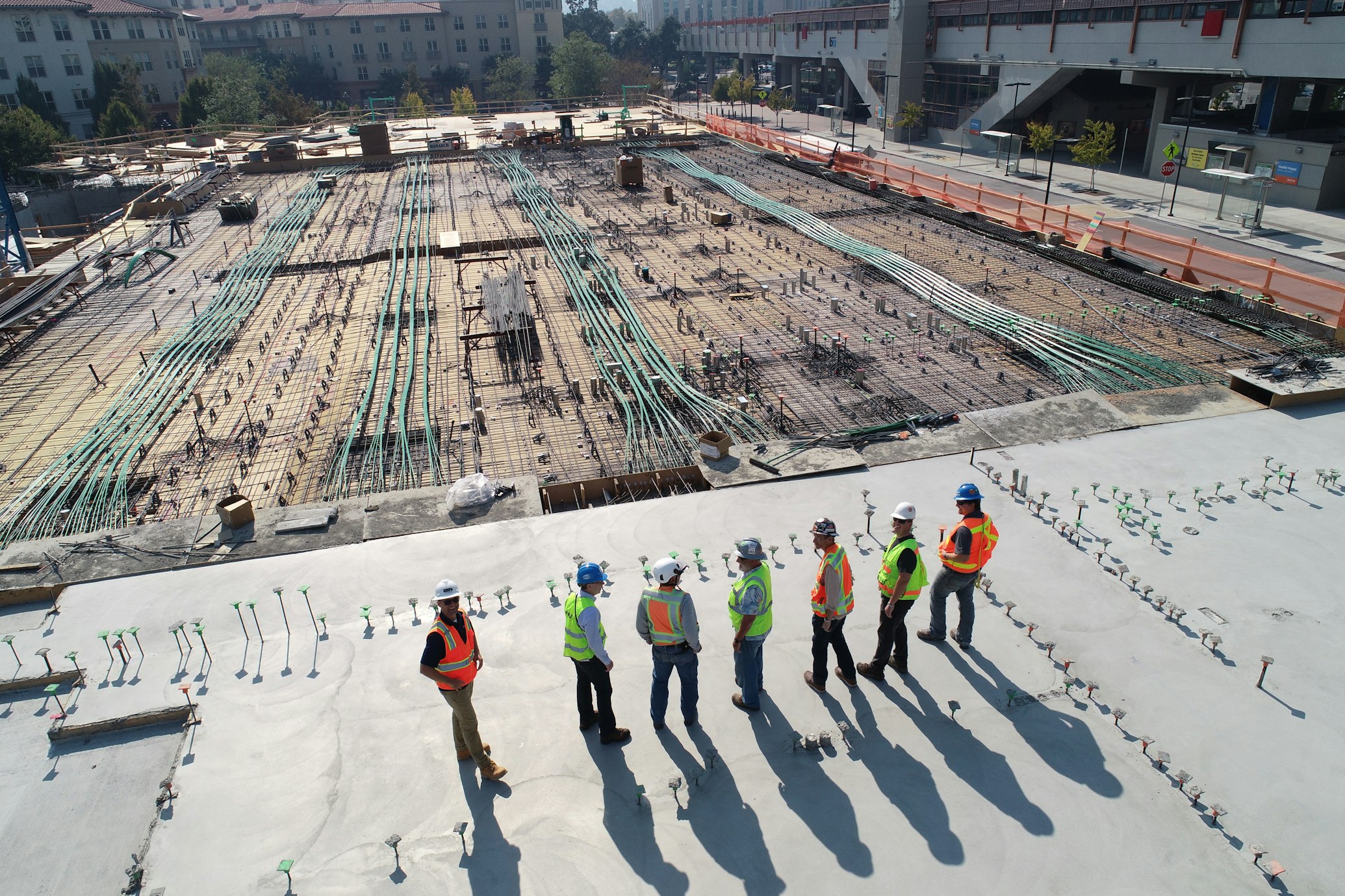 Construction workers with hard hats working on building site with cranes in background
